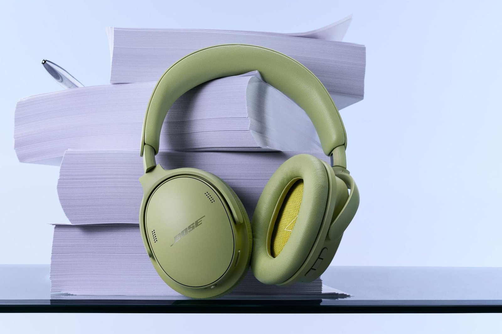 The second-generation Bose QuietComfort ANC headphones in green hanging off a stack of paper.