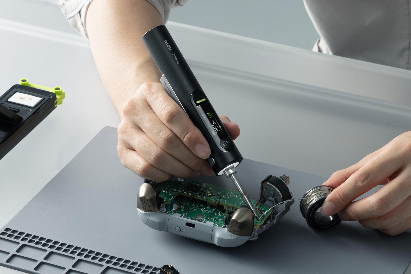 A person using Hoto’s soldering iron to repair a video game controller.