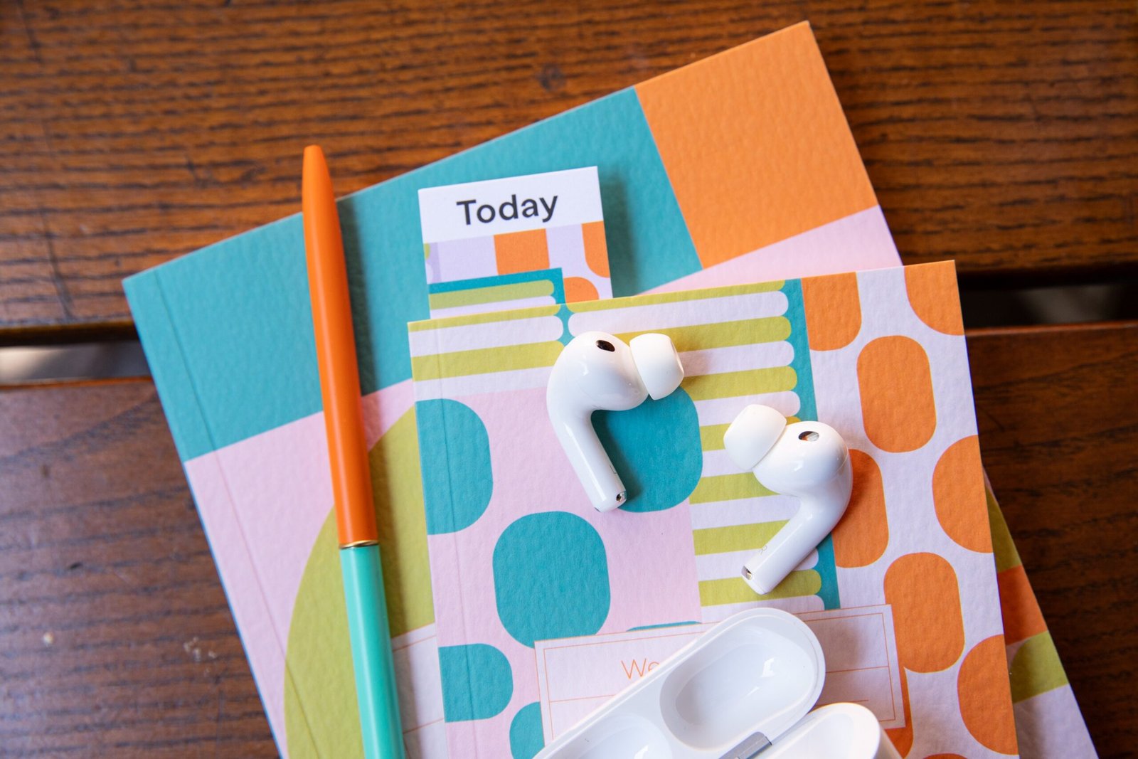 AirPods Pro 3 on some colorful notebooks.