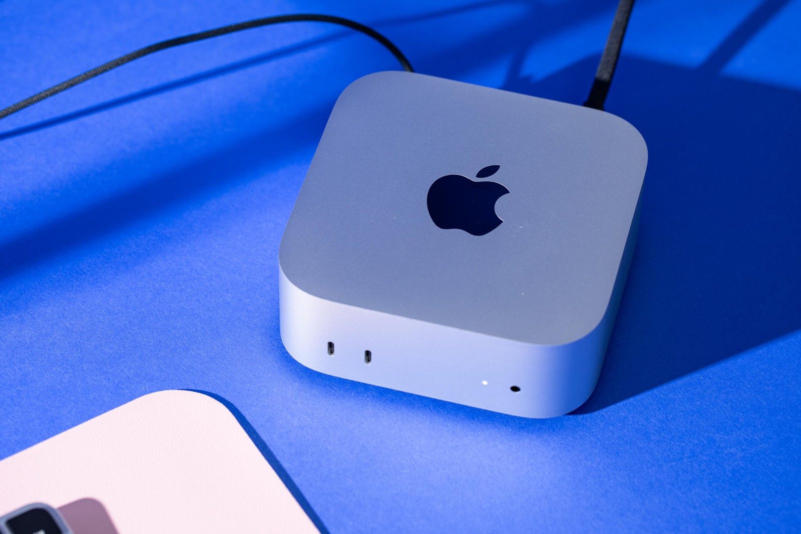A silver Mac Mini on a blue background.