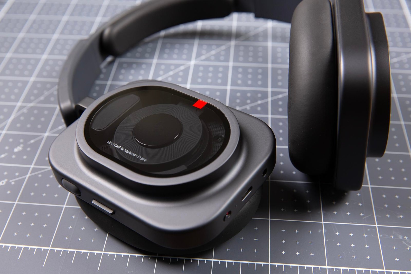 Nothing Pro 1 headphones sitting on a gridded surface.