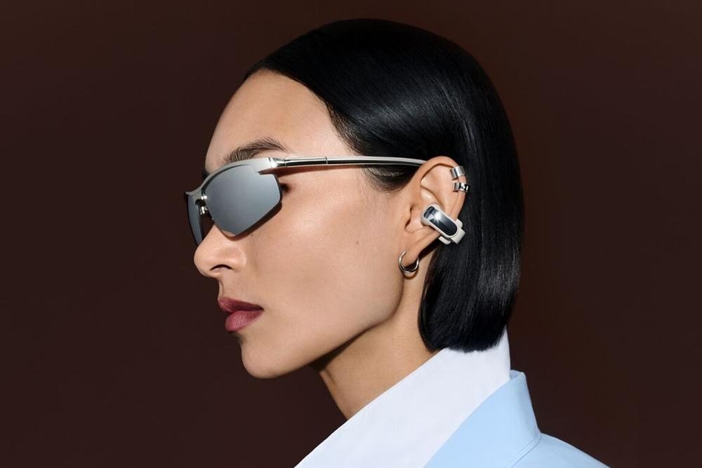 A person in sunglasses wears the Bose Ultra Open Earbuds (2nd Gen) clipped to their ear.