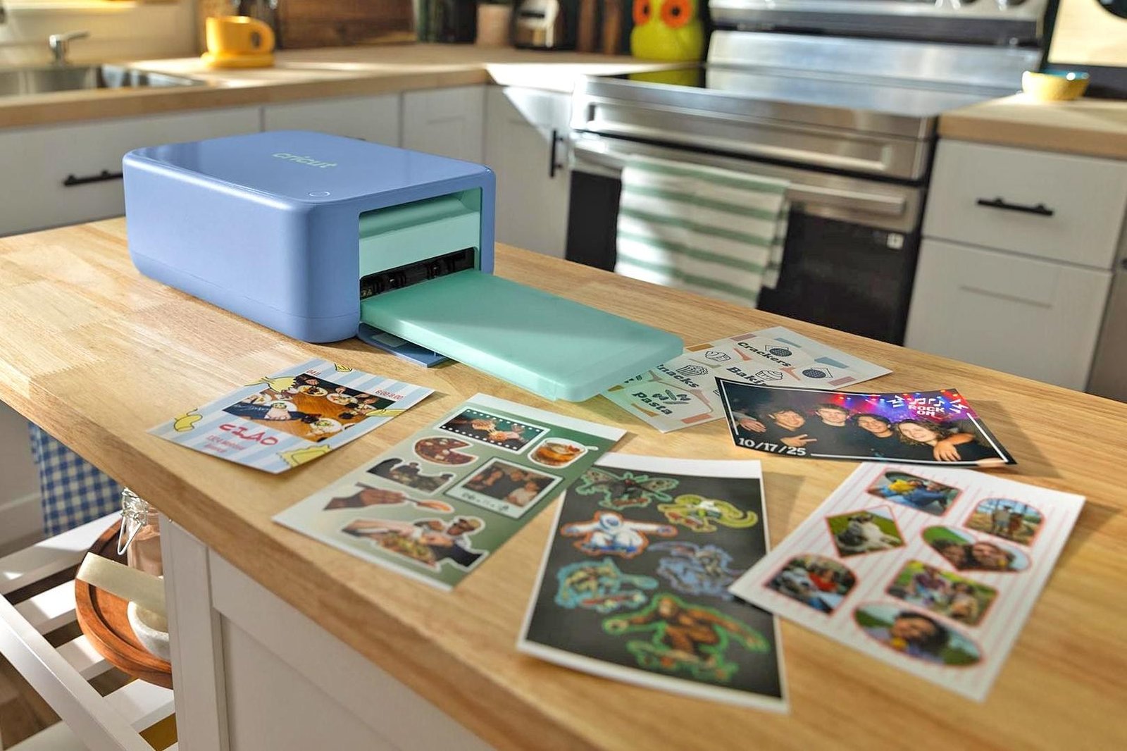 One of Cricut’s new StickerPix machines on a kitchen island surrounded by printed sticker sheets.