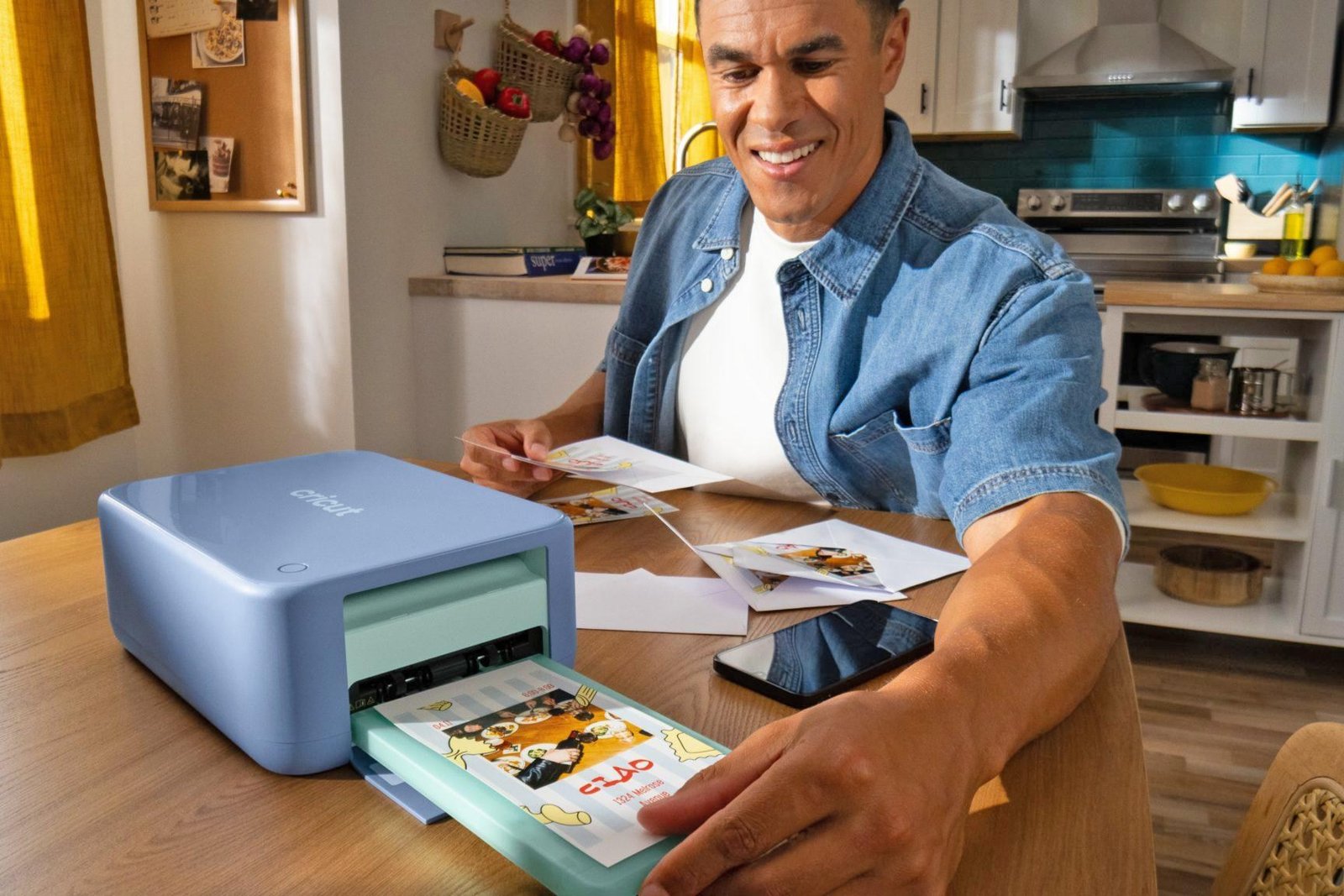A person removes a print from the Cricut StickerPix Print plus Cut crafting machine being used on a kitchen table. A person removes a print from the Cricut StickerPix Print plus Cut crafting machine being used on a kitchen table.