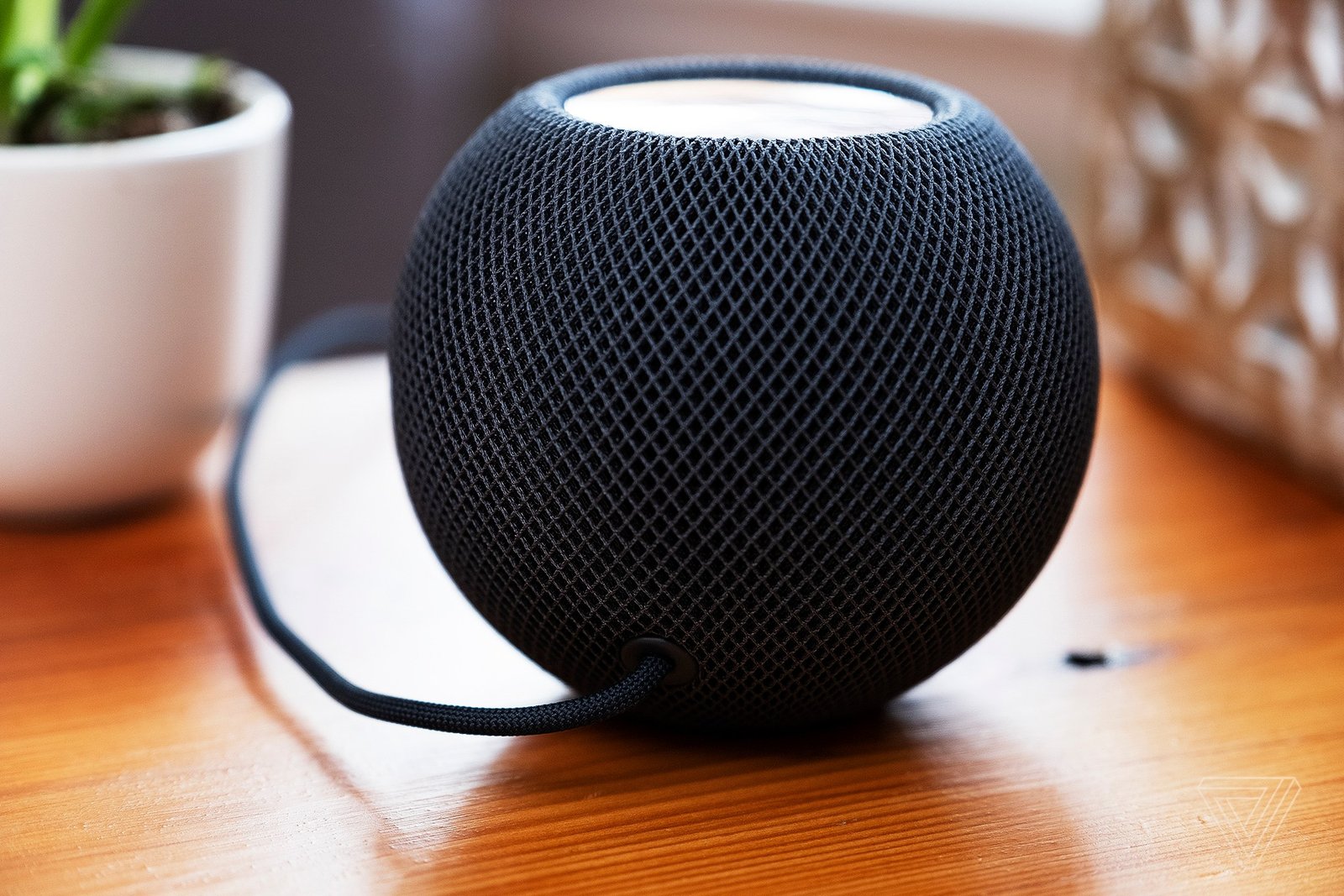 The original Apple HomePod Mini on a wooden table.