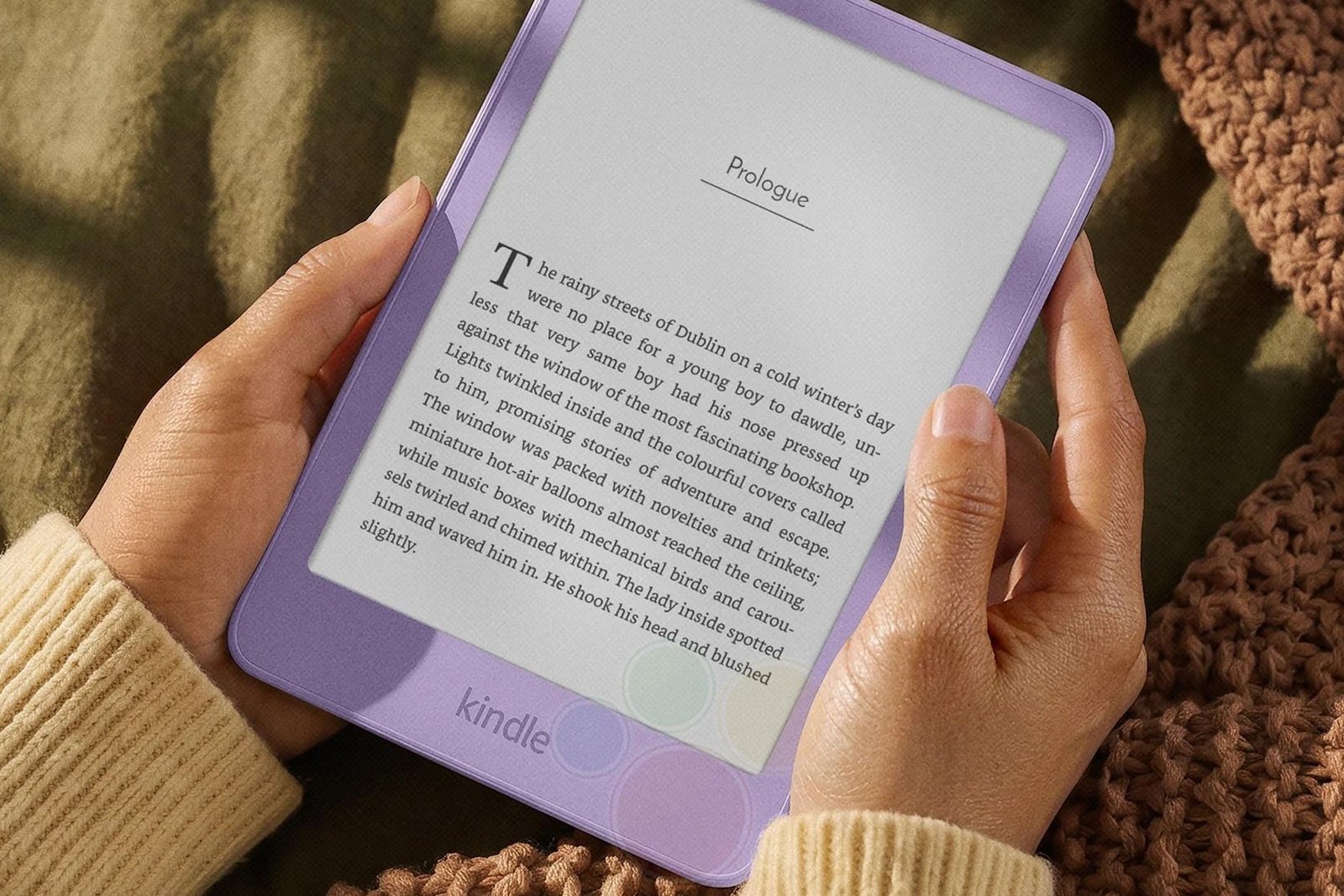 A person holds an Amazon Kindle e-reader in two hands.