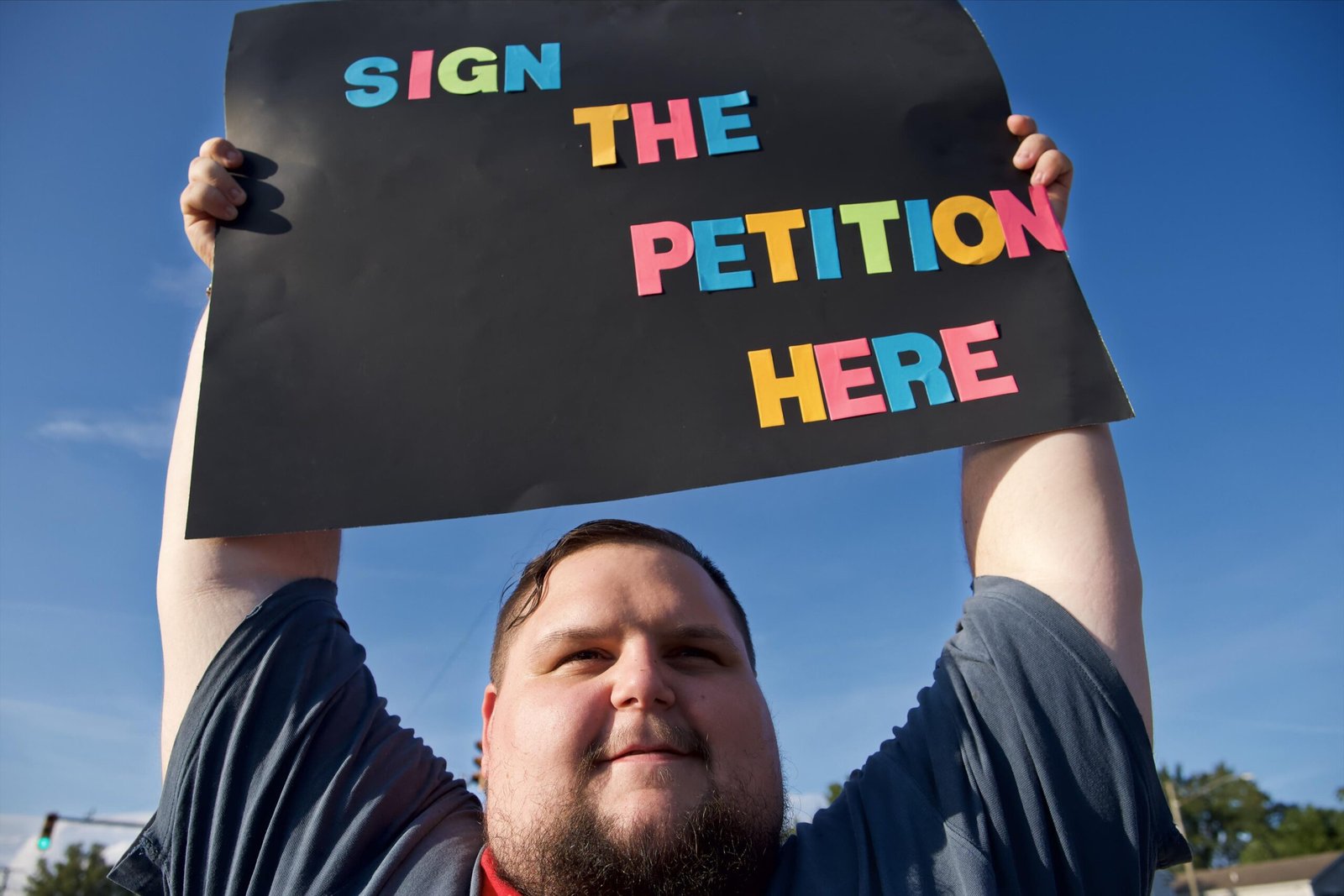 Close portrait of Rufus holding “Sign the petition here” sign.