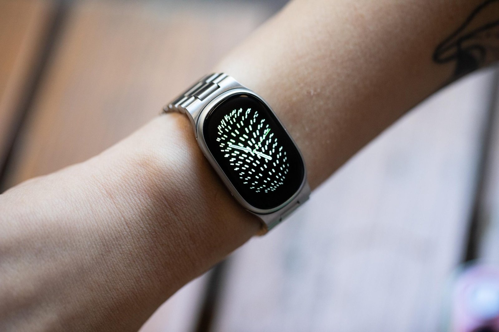 Close up of the Fitbit Edge on a person’s wrist with the new metal links bracelet and a watchface that shows noticeable black bezels around the edge.