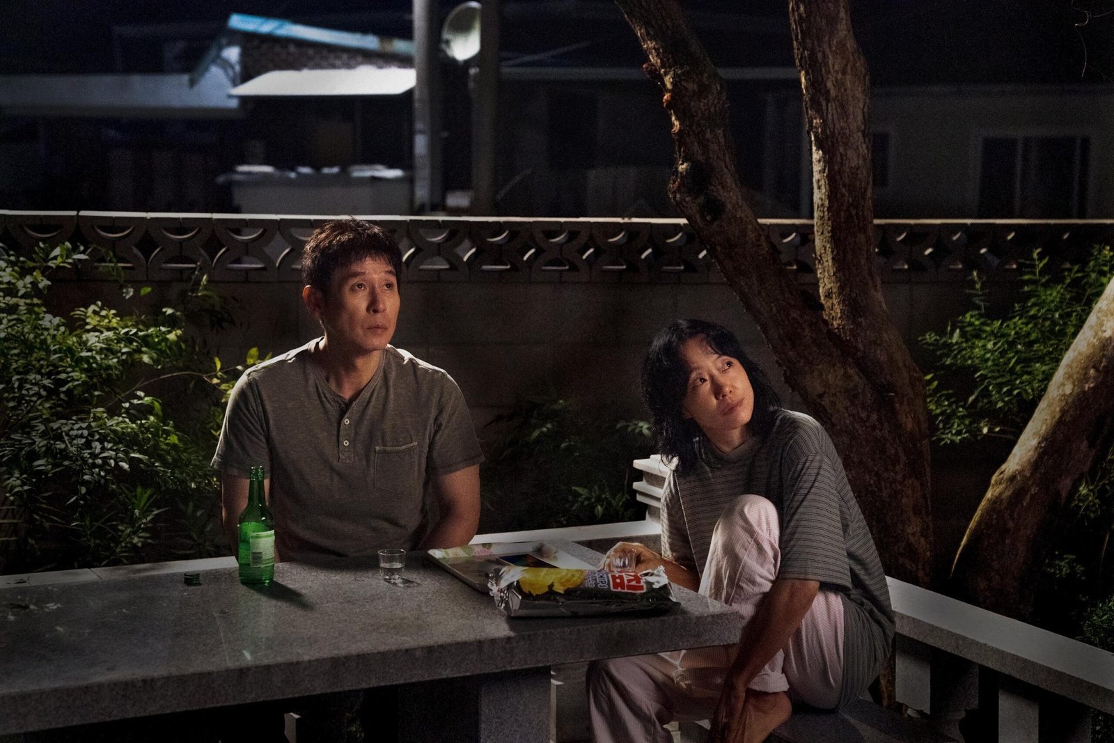 a man and a woman at a table outside in the dark