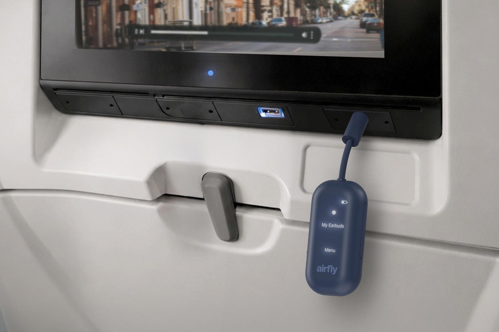 The Twelve South Airfly View wireless dongle is connected to the headphone jack on an in-flight entertainment system.