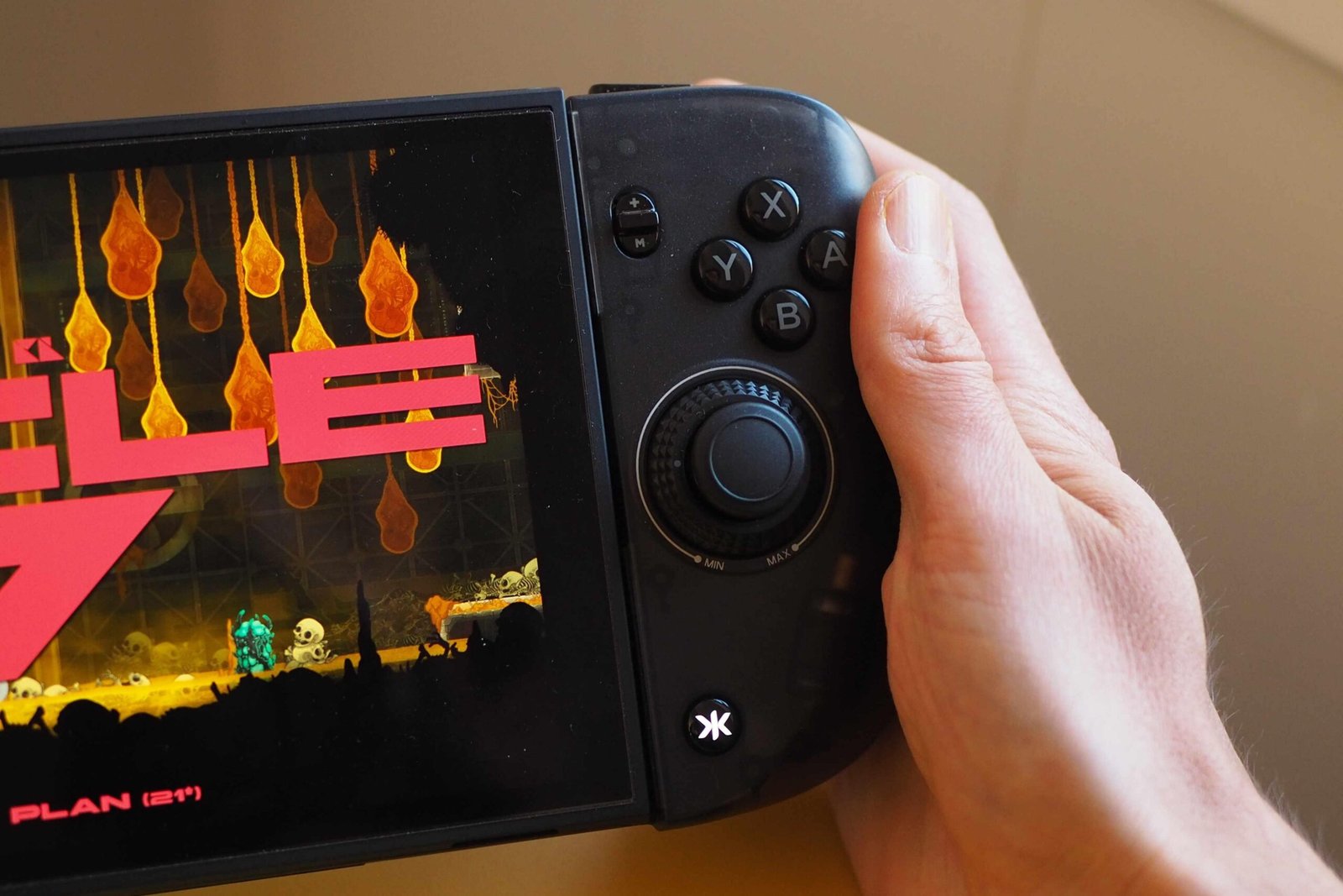 A close-up photo of the Crkd Nitro Deck 2, showing the face buttons and right analog stick. The Nintendo Switch 2 console held by the accessory is displaying the game Echo Weaver.